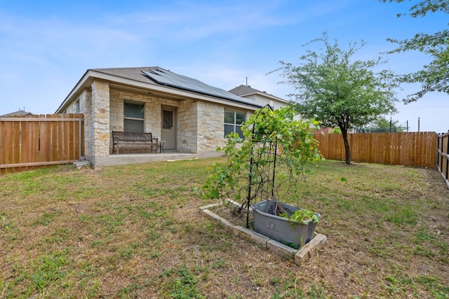 11117 Boundless Valley Dr, Austin, TX 78754 - rear view of house with roof mounted solar panels, stone siding, and a patio area