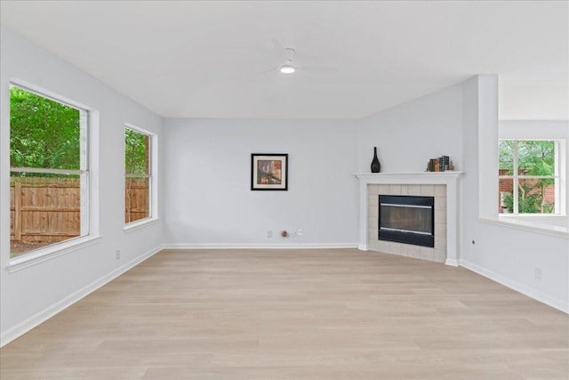 16900 Abyssinian Ln, Round Rock, TX 78681 - unfurnished living room featuring plenty of natural light, light wood-style flooring, baseboards, and a tiled fireplace