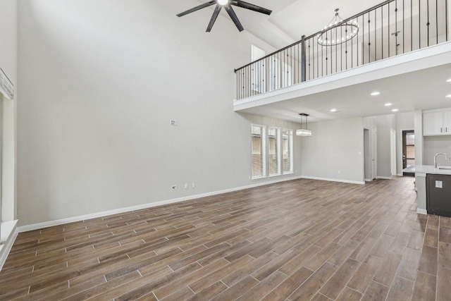125 Bauer Loop, Liberty Hill, TX 78642 - unfurnished living room with a high ceiling, a ceiling fan, dark wood-style floors, a chandelier, and recessed lighting