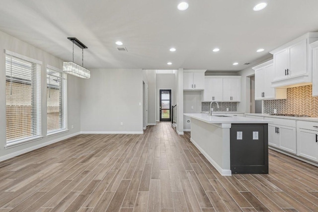 125 Bauer Loop, Liberty Hill, TX 78642 - kitchen featuring light wood finished floors, light countertops, an island with sink, backsplash, and recessed lighting