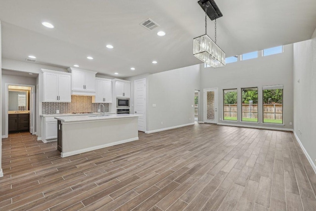 125 Bauer Loop, Liberty Hill, TX 78642 - kitchen with stainless steel appliances, open floor plan, light countertops, a chandelier, and a center island with sink