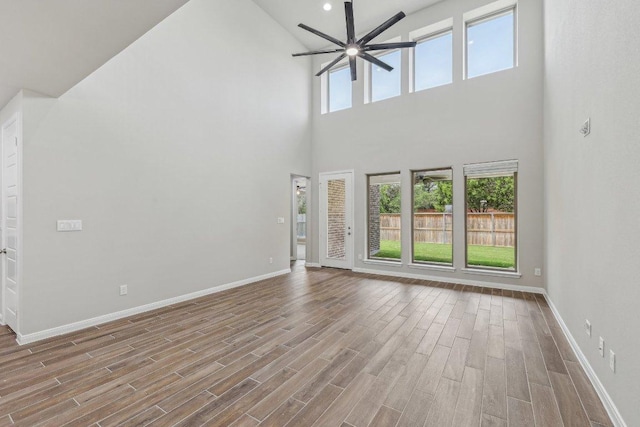 125 Bauer Loop, Liberty Hill, TX 78642 - unfurnished living room featuring a towering ceiling, ceiling fan, plenty of natural light, and wood finished floors