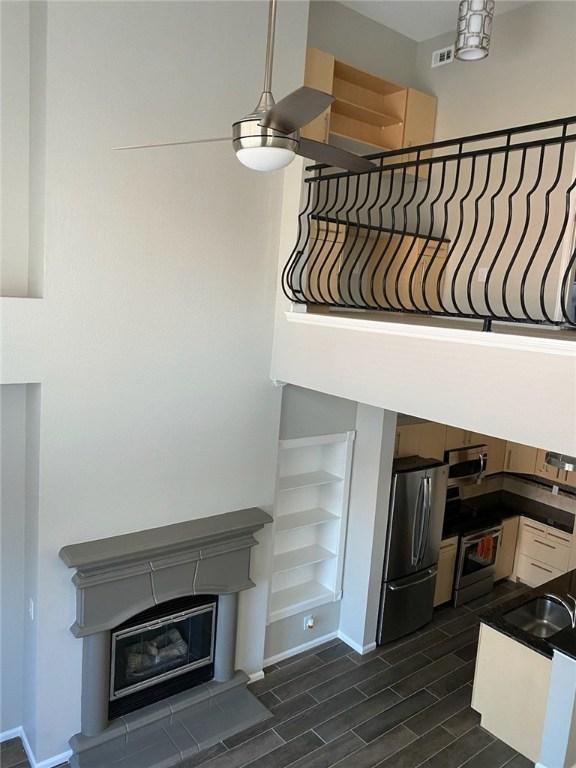11203 Ranch Road 2222nd Rd Unit 901, Austin, TX 78730 - stairs featuring wood finish floors, built in shelves, baseboards, a glass covered fireplace, and a ceiling fan