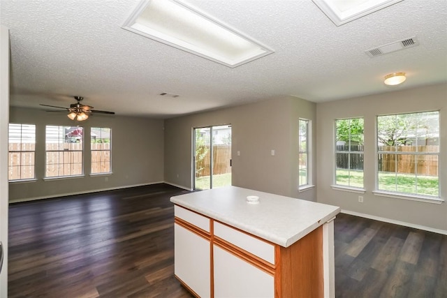 501 Thicket Ln, Kyle, TX 78640 - kitchen featuring a textured ceiling, open floor plan, dark wood-type flooring, baseboards, and light countertops