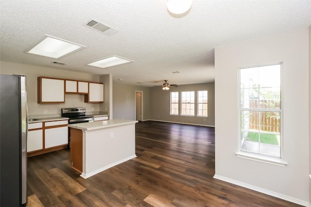 501 Thicket Ln, Kyle, TX 78640 - kitchen with appliances with stainless steel finishes, light countertops, a textured ceiling, a center island, and dark wood-style floors