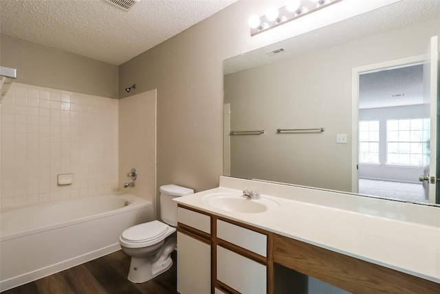 501 Thicket Ln, Kyle, TX 78640 - full bath featuring toilet, wood finished floors, vanity, a textured ceiling, and bathtub / shower combination
