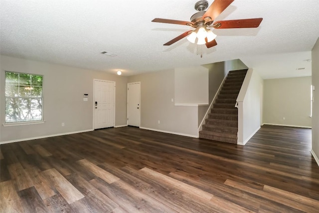 501 Thicket Ln, Kyle, TX 78640 - unfurnished living room with stairs, a ceiling fan, dark wood-style flooring, baseboards, and a textured ceiling