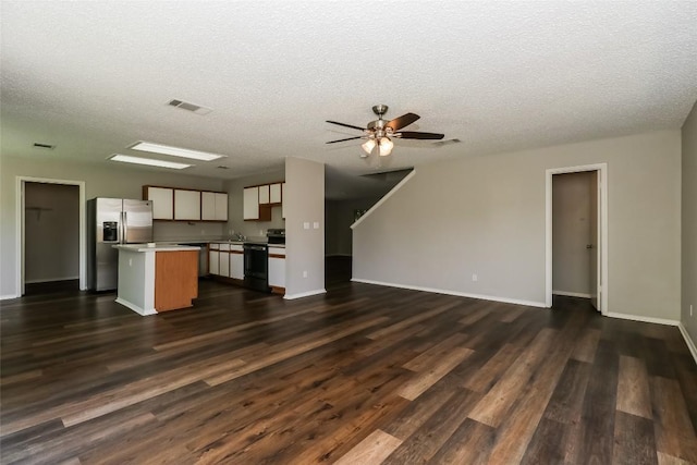 501 Thicket Ln, Kyle, TX 78640 - unfurnished living room featuring dark wood-style floors, a textured ceiling, ceiling fan, baseboards, and a sink