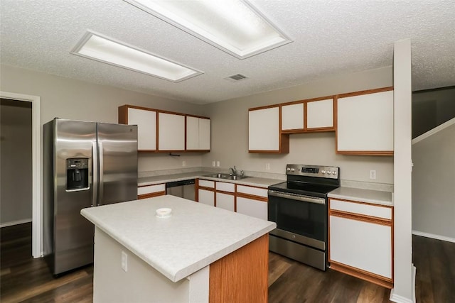 501 Thicket Ln, Kyle, TX 78640 - kitchen with appliances with stainless steel finishes, dark wood finished floors, a textured ceiling, light countertops, and a sink