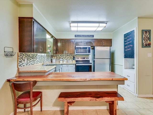 1576 Westview Court Dr, Canyon Lake, TX 78133 - kitchen with appliances with stainless steel finishes, a peninsula, backsplash, ornamental molding, and dark brown cabinetry