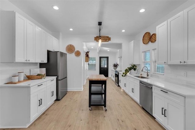776 Butcher St, New Braunfels, TX 78130 - kitchen with stainless steel appliances, a sink, light countertops, light wood-style floors, and white cabinets
