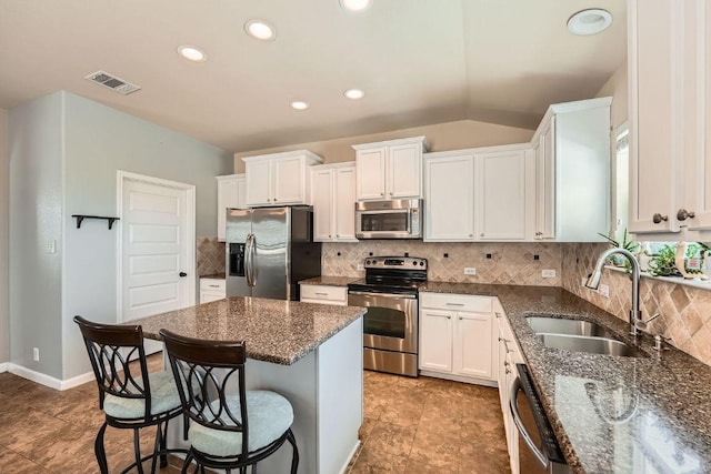 134 Sassafras St, Hutto, TX 78634 - kitchen with appliances with stainless steel finishes, a sink, a kitchen bar, white cabinetry, and lofted ceiling