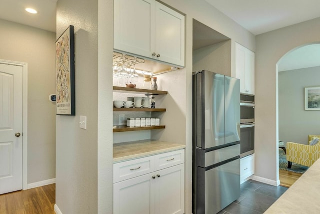 1125 Byers Ln, Austin, TX 78753 - kitchen featuring appliances with stainless steel finishes, arched walkways, light countertops, white cabinetry, and recessed lighting