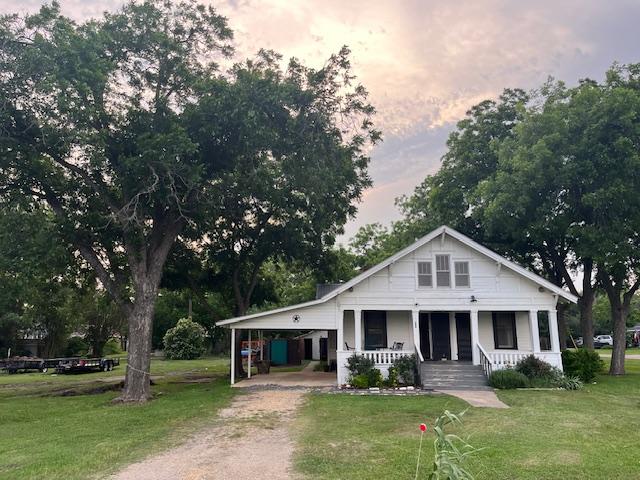 200 N Walton St, Granger, TX 76530 - bungalow-style home featuring an attached carport, covered porch, driveway, and a front lawn