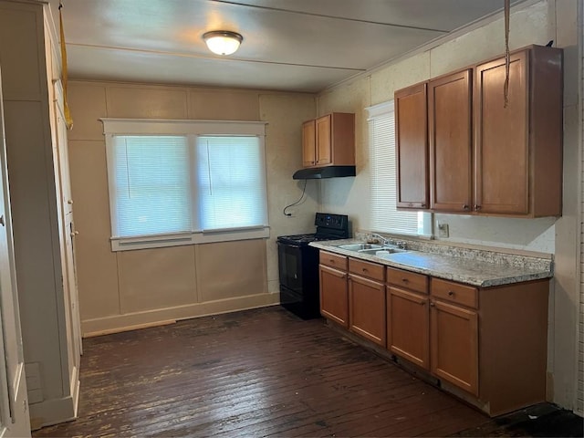 200 N Walton St, Granger, TX 76530 - kitchen with black electric range, dark wood-type flooring, under cabinet range hood, brown cabinets, and light countertops