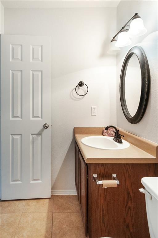913 Cindy Ln, Leander, TX 78641 - half bathroom featuring vanity, tile patterned flooring, toilet, and baseboards