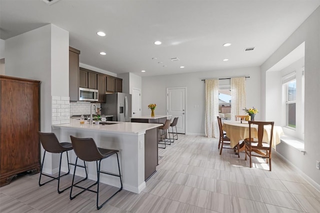8212 Daisy Cutter Xing, Georgetown, TX 78626 - kitchen with appliances with stainless steel finishes, a sink, a breakfast bar, light countertops, and backsplash