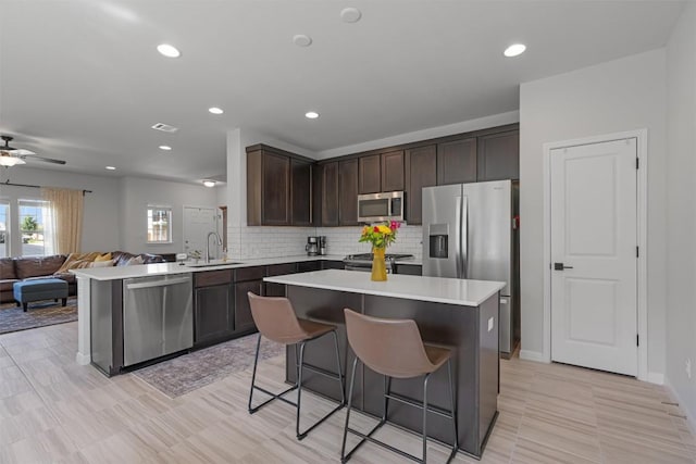 8212 Daisy Cutter Xing, Georgetown, TX 78626 - kitchen with stainless steel appliances, a sink, open floor plan, dark brown cabinetry, and a breakfast bar area