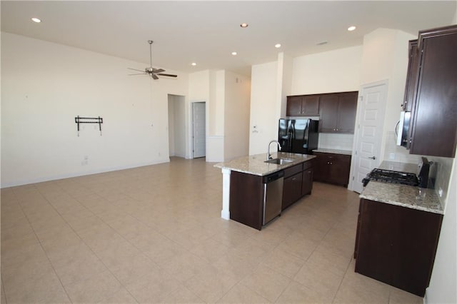 2204 Cabrillo Path, Leander, TX 78641 - kitchen with appliances with stainless steel finishes, a ceiling fan, a kitchen island with sink, decorative backsplash, and dark brown cabinets