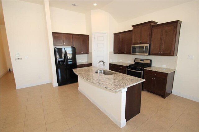2204 Cabrillo Path, Leander, TX 78641 - kitchen featuring stainless steel appliances, dark brown cabinets, an island with sink, light tile patterned flooring, and high vaulted ceiling