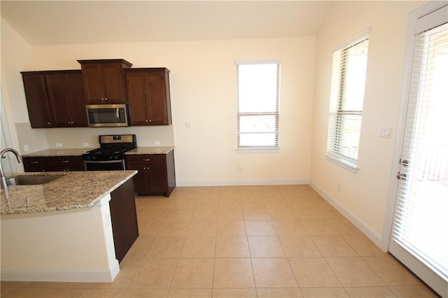 2204 Cabrillo Path, Leander, TX 78641 - kitchen with appliances with stainless steel finishes, tasteful backsplash, light stone counters, dark brown cabinets, and light tile patterned flooring