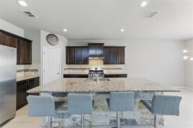 6739 Indian Lndg, San Antonio, TX 78253 - kitchen with appliances with stainless steel finishes, an island with sink, light stone counters, tasteful backsplash, and a kitchen bar