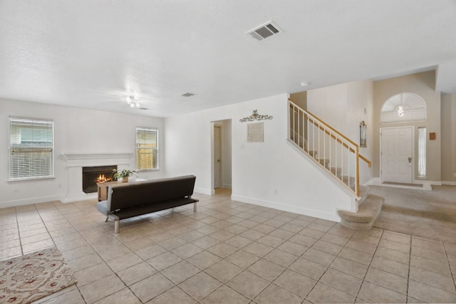 2917 Feathercrest Dr, Austin, TX 78728 - living room featuring stairway, light tile patterned floors, and a warm lit fireplace