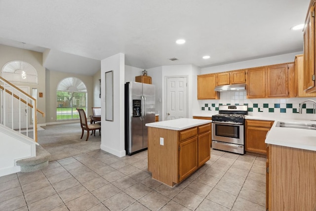 2917 Feathercrest Dr, Austin, TX 78728 - kitchen with appliances with stainless steel finishes, under cabinet range hood, light tile patterned floors, a center island, and light countertops