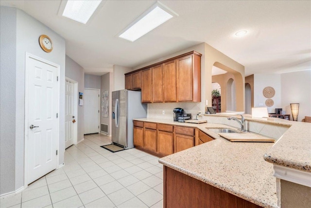 15115 Staked Plains Loop, Austin, TX 78717 - kitchen featuring stainless steel refrigerator with ice dispenser, a sink, light tile patterned floors, light stone counters, and a peninsula