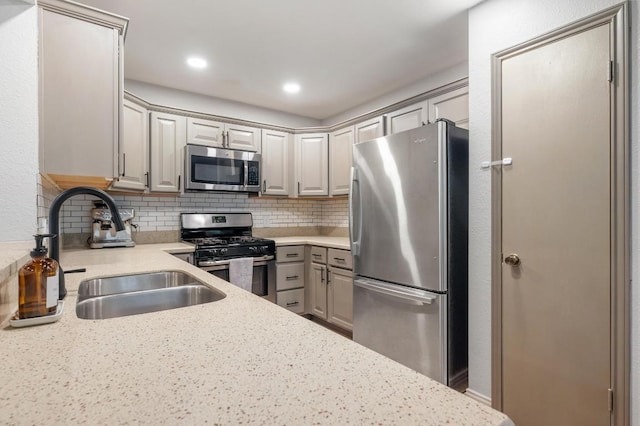 12721 Heinemann Dr, Austin, TX 78727 - kitchen featuring stainless steel appliances, a sink, gray cabinetry, tasteful backsplash, and light stone counters