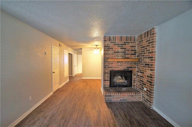 1320 Southport Dr, Austin, TX 78704 - unfurnished living room featuring a textured ceiling, ceiling fan, wood finished floors, a brick fireplace, and baseboards