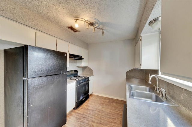 1320 Southport Dr, Austin, TX 78704 - kitchen featuring black appliances, a sink, under cabinet range hood, a textured ceiling, and white cabinetry