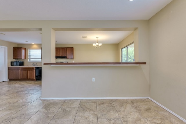 8912 Norwich Castle, Austin, TX 78747 - kitchen with black appliances, brown cabinets, baseboards, under cabinet range hood, and a chandelier
