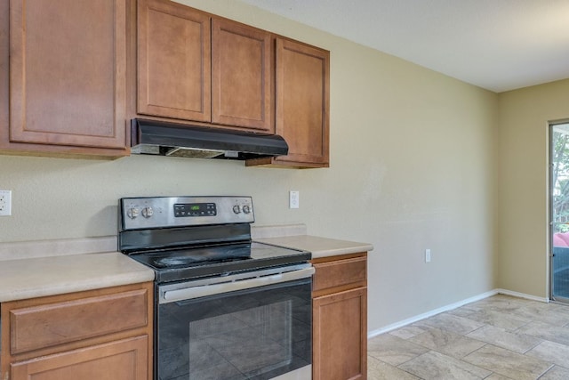 8912 Norwich Castle, Austin, TX 78747 - kitchen with electric stove, under cabinet range hood, light countertops, and brown cabinetry