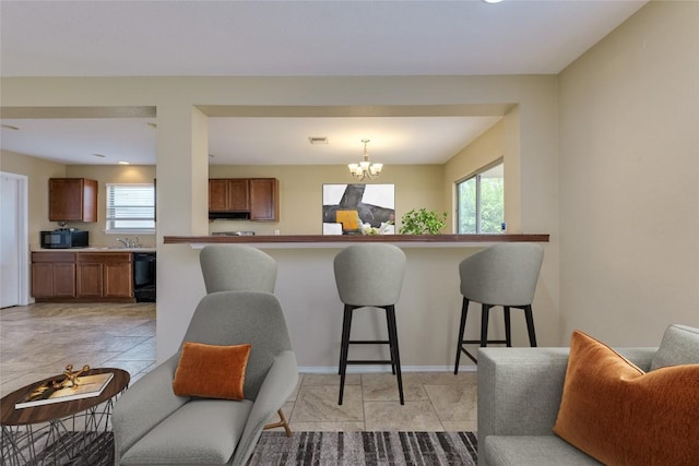 8912 Norwich Castle, Austin, TX 78747 - kitchen with black microwave, brown cabinetry, a kitchen breakfast bar, a chandelier, and pendant lighting