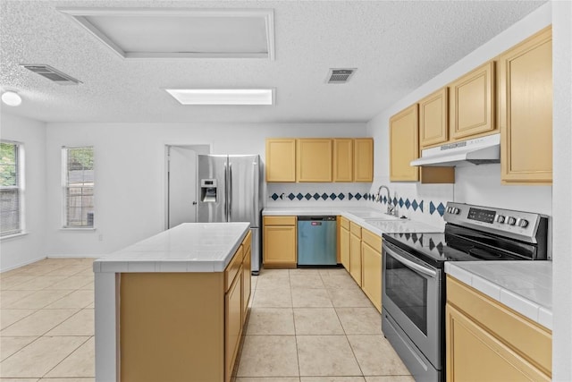 491 Emerald Fields Ln, Kyle, TX 78640 - kitchen featuring stainless steel appliances, under cabinet range hood, tile counters, a sink, and light tile patterned floors