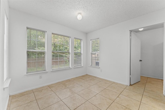491 Emerald Fields Ln, Kyle, TX 78640 - unfurnished room with a textured ceiling, light tile patterned flooring, and baseboards