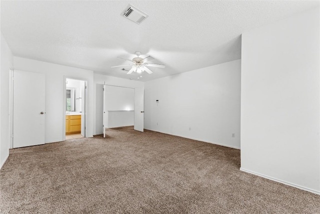 491 Emerald Fields Ln, Kyle, TX 78640 - unfurnished bedroom with light carpet, connected bathroom, a textured ceiling, ceiling fan, and baseboards