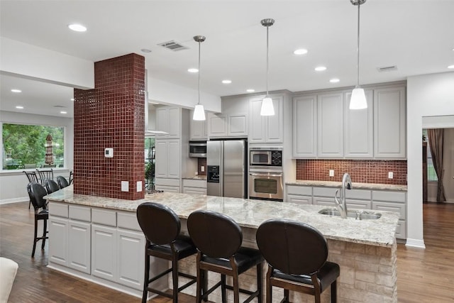 2603 Pearce Rd, Austin, TX 78730 - kitchen with stainless steel appliances, a sink, decorative backsplash, dark wood-type flooring, and a kitchen bar
