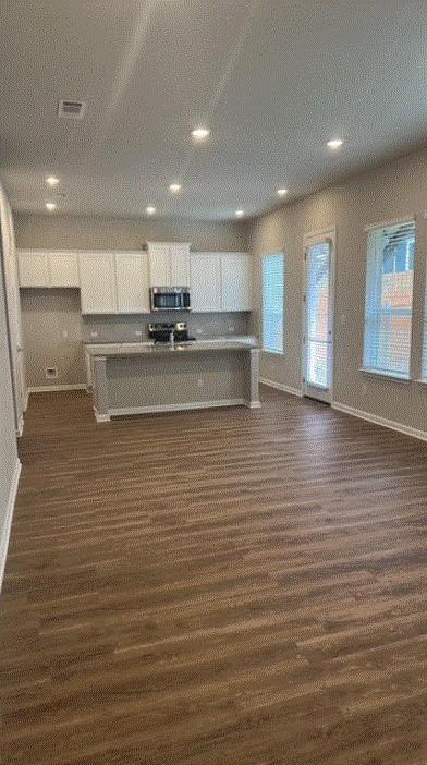 1020 Vista View Dr Unit 2001, Georgetown, TX 78626 - kitchen with stainless steel microwave, white cabinets, baseboards, recessed lighting, and dark wood-style flooring