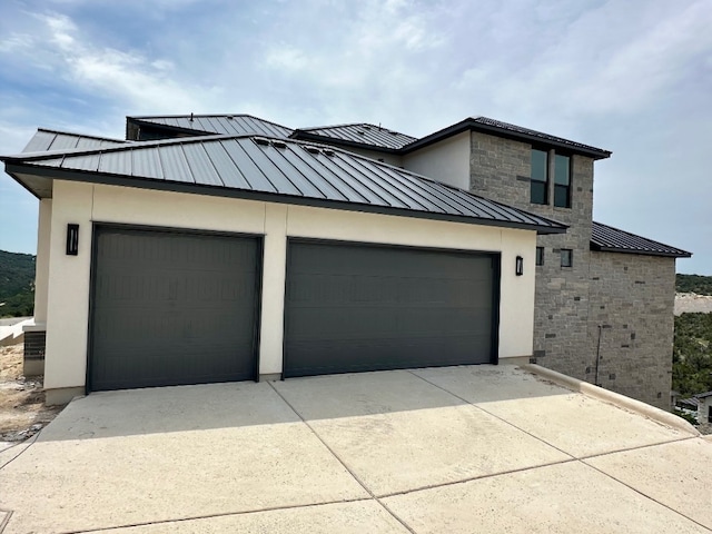 104 High View Trl, Lakeway, TX 78738 - view of front of house with a standing seam roof, driveway, metal roof, stucco siding, and an attached garage