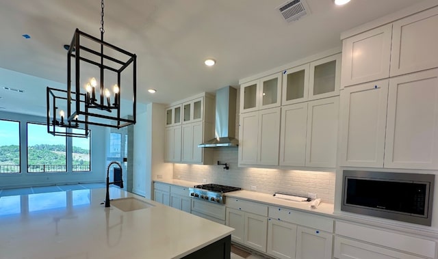 104 High View Trl, Lakeway, TX 78738 - kitchen with wall chimney exhaust hood, appliances with stainless steel finishes, decorative backsplash, light countertops, and a chandelier