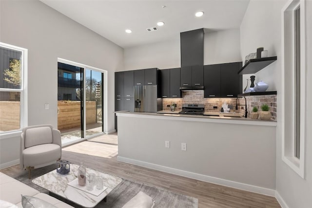 4510 Terry-O Ln Unit 108, Austin, TX 78745 - kitchen featuring dark cabinetry, open shelves, appliances with stainless steel finishes, a peninsula, and light wood-style floors