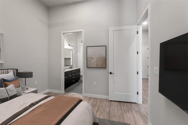 4510 Terry-O Ln Unit 108, Austin, TX 78745 - bedroom featuring light wood-type flooring, a sink, baseboards, a towering ceiling, and connected bathroom