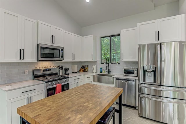 600 Blackson Ave Unit 2, Austin, TX 78752 - kitchen with appliances with stainless steel finishes, vaulted ceiling, decorative backsplash, white cabinets, and recessed lighting