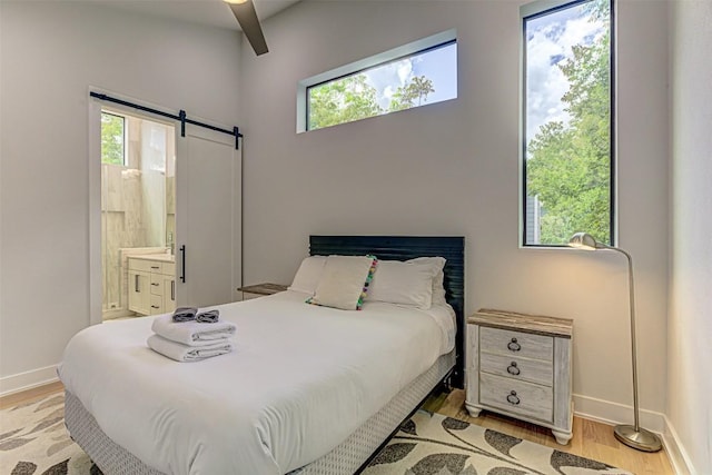600 Blackson Ave Unit 2, Austin, TX 78752 - bedroom featuring a barn door, light wood-style floors, and baseboards