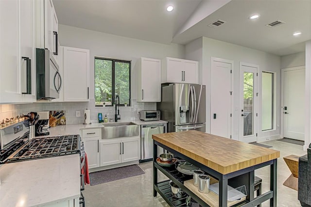 600 Blackson Ave Unit 2, Austin, TX 78752 - kitchen featuring appliances with stainless steel finishes, a sink, decorative backsplash, white cabinets, and recessed lighting