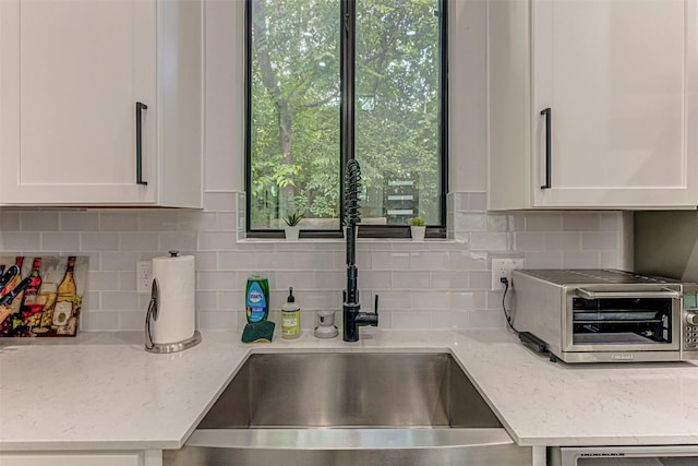 600 Blackson Ave Unit 2, Austin, TX 78752 - kitchen with a sink, white cabinetry, tasteful backsplash, and light stone counters