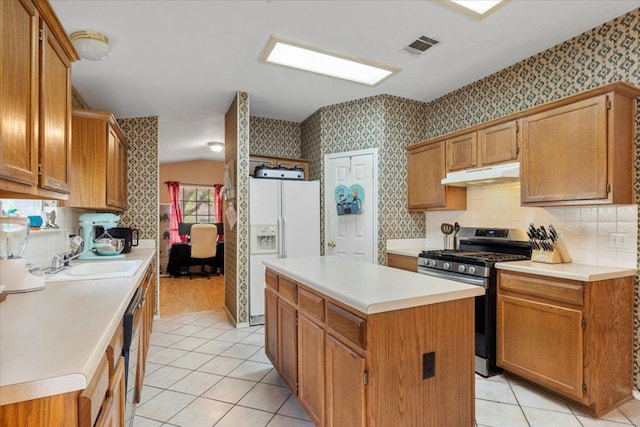 4125 Licorice Ln, Austin, TX 78728 - kitchen featuring gas stove, under cabinet range hood, white fridge with ice dispenser, wallpapered walls, and light tile patterned floors