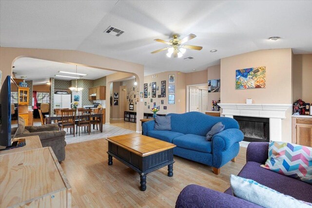 4125 Licorice Ln, Austin, TX 78728 - living room with a ceiling fan, lofted ceiling, a glass covered fireplace, light wood-style flooring, and arched walkways